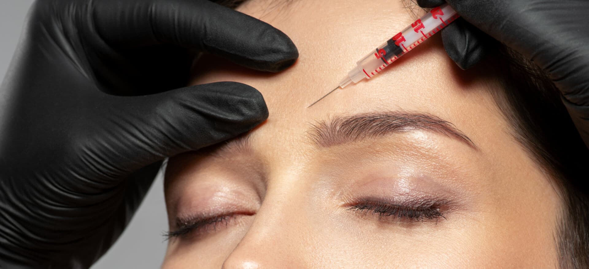 Young caucasian woman getting botox cosmetic injection in a forehead
